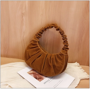 Detail van caramel suède hobo tas met geplooid handvat en fijne lederen textuur