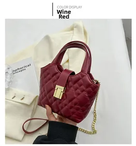 Close-up of wine red quilted mini bag with gold chain strap and metal buckle detail
