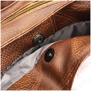 Close-up of vintage brown leather bag featuring silver magnetic snap button and lining