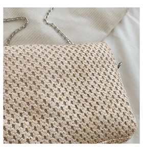 Close-up of beige woven straw bag texture with elegant silver metal chain strap detail