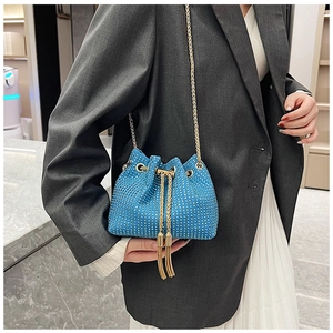 Détail d'un sac seau bleu orné de strass avec bandoulière chaîne dorée sur un mannequin
