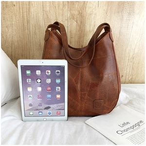 Brown vintage leather tote bag showing large capacity by placing an iPad inside