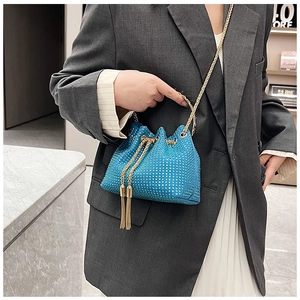 Détail du sac seau bleu en strass avec bandoulière dorée et fermeture à pompon élégante