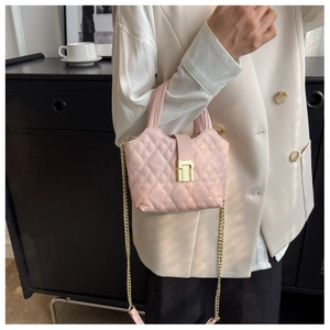 Detail of a mini pink quilted crossbody bag with gold hardware and chain strap