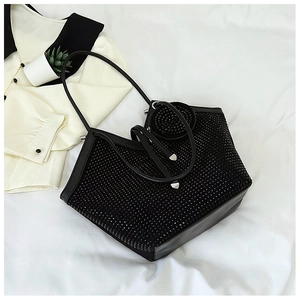 Flat lay of black rhinestone tote bag with a small round pouch on white bedding background