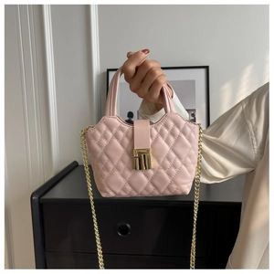 Close-up of light pink quilted handbag with gold hardware and chain strap