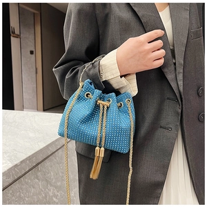 Détail du sac seau bleu orné de strass avec chaîne dorée et détails de pompons