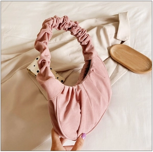 Roze geplooide wolkentas met zachte textuur getoond in een lifestyle platte lay-out