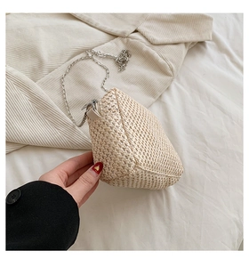 Close-up of woven straw cloud bag featuring silver metal chain and natural textures
