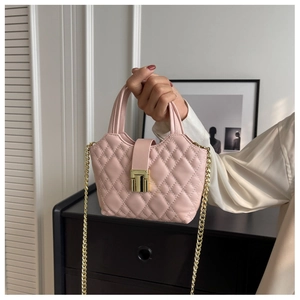 Detail of light pink quilted handbag with gold metal lock and chain strap held by hand