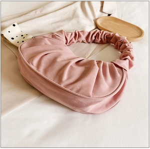 Detail van de roze geplooide cloud bag met zachte handvatten op een houten dienblad