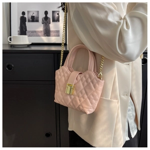 Detail of light pink quilted handbag with gold chain strap and metallic lock on model