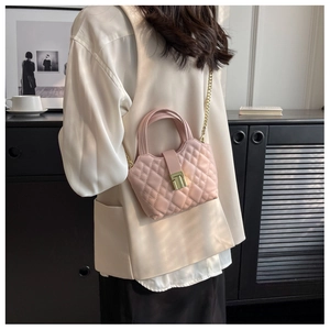 Detail shot of a pink quilted mini bag with golden chain strap and metal lock closure
