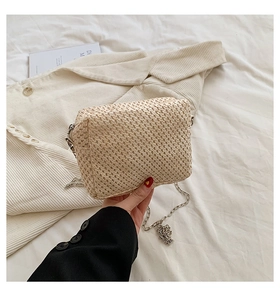 Detailed view of beige straw woven texture on rectangular bag with silver chain strap