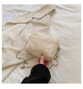 Detailed close-up of cream woven straw bag with textured surface and silver chain strap