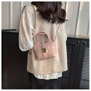 Close-up of pink quilted mini bag with gold chain strap and metal lock detail