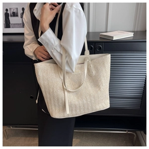 Détail du sac cabas tissé beige avec un écusson logo en cuir circulaire et doubles poignées