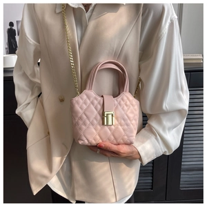 Detail of light pink quilted mini handbag with gold metal lock and chain strap