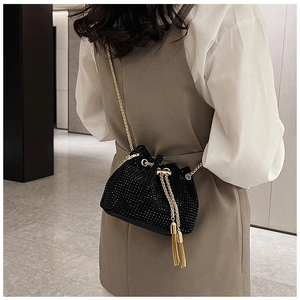 Vue détaillée du sac seau noir en strass avec chaîne dorée et franges sur modèle