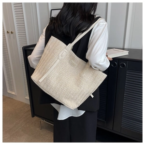Détail du sac cabas tissé crème montrant la texture chevron et les fines anses