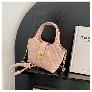Detail of light pink quilted handbag with gold clasp and elegant metal chain strap