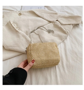 Detail of hand-woven straw bag texture with elegant silver chain shoulder strap