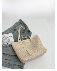 Détail du sac cabas en paille blanc cassé avec texture ondulée et longues anses