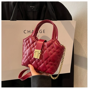 Close-up of burgundy quilted handbag with gold metal lock and chain strap detail
