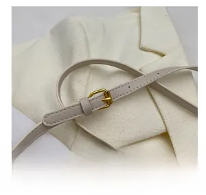 Close-up of adjustable strap with gold buckle on cream straw tote bag