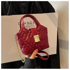 Detail of wine red quilted mini bag featuring gold hardware and chain strap