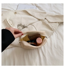 Detail view of woven straw bag interior with metal chain and room for daily essentials
