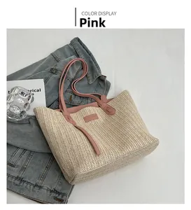Détail de la sangle en cuir rose et du tissage de paille beige d'un grand sac cabas fourre-tout