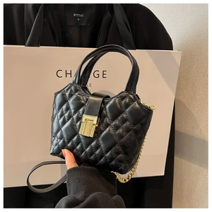 Detail of black quilted mini bucket bag with gold chain strap and metallic clasp