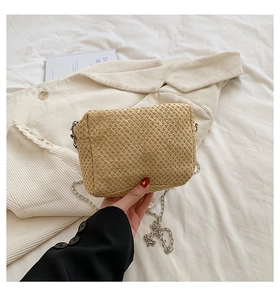 Detail of hand-woven straw crossbody bag with elegant silver metal chain strap