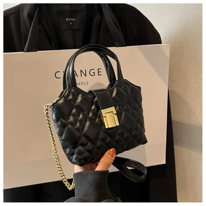 Detailed close-up of a mini quilted black handbag with gold metal clasp and chain strap