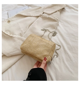 Detailed macro shot of natural straw texture and silver chain strap on the beige bag