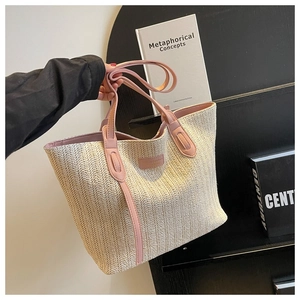Détail de la texture d'un sac cabas en paille tissée avec anses en cuir rose et plaque