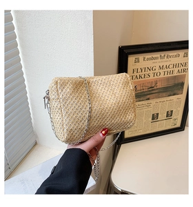 Detailed view of handmade woven straw crossbody bag with silver metal chain strap for summer