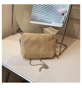Detail of straw shoulder bag with woven texture and a silver metal chain strap