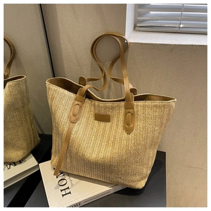 Détail du sac cabas en paille tressée à chevrons avec des poignées en cuir marron