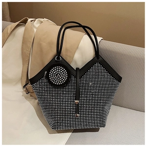 Close-up of a sparkling rhinestone tote bag on a grey sofa with a mini coin purse