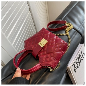 Detail of deep red quilted leather bag with golden twist lock and chain strap