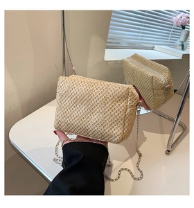 Detail view of woven straw crossbody bag with silver chain strap and mirror reflection