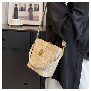 Detail view of woven straw bucket bag with leather trim and gold metal buckle clasp