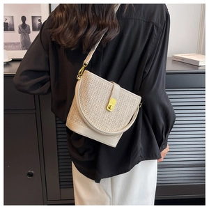Detail of bohemian straw bucket bag showing metal twist lock and beige leather trim