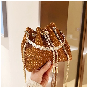Détail du sac seau en daim marron avec strass dorés et chaîne décorative à pompons en métal