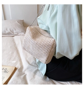Detail of cream woven crossbody bag with silver chain strap shown in a lifestyle setting