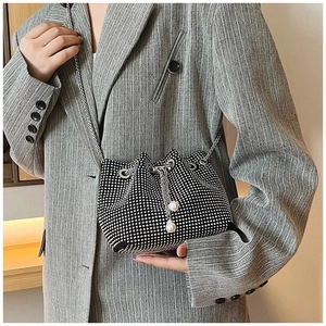 Détail du sac seau noir en strass avec chaîne argentée et breloques perles blanches