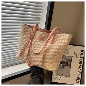 Détail d'un grand sac cabas tissé avec des anses roses et une texture de paille