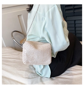 Detailed view of cream straw crossbody bag with silver chain strap on model